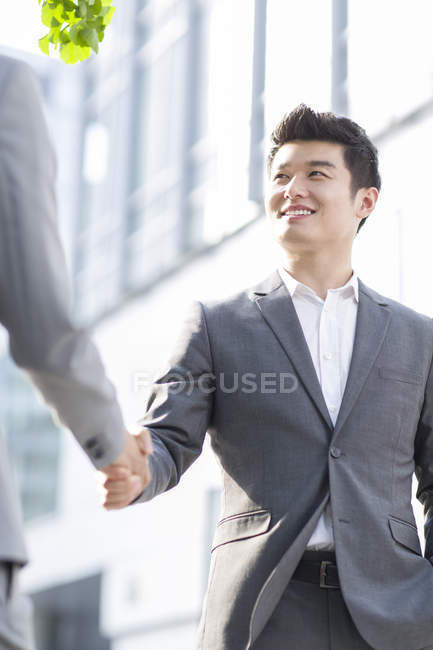 Empresários chineses apertando as mãos na rua — Fotografia de Stock