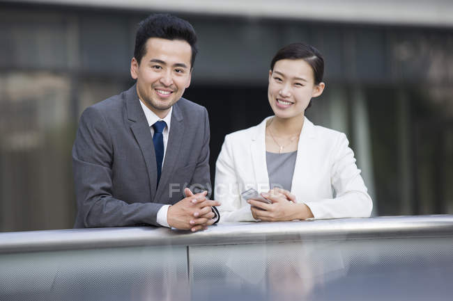 Chinese businessman and businesswoman looking in camera on street — Stock Photo
