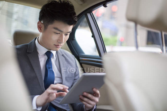 Chinesischer Geschäftsmann nutzt digitales Tablet im Auto — Stockfoto
