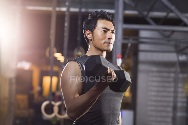 Hombre chino levantando mancuerna en el gimnasio - foto de stock