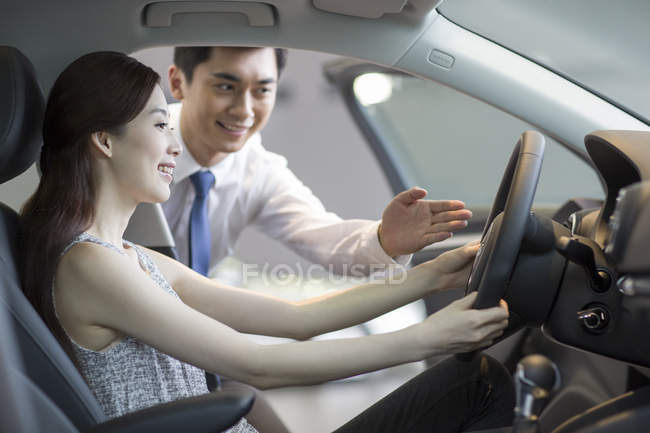 Chinese woman taking test drive with car dealer assistance — Stock Photo