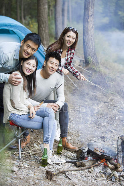 Amigos chineses sentados ao lado da fogueira e preparando comida — Fotografia de Stock