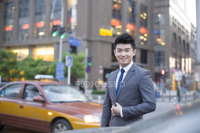 Chinese businessman standing on street at car — Stock Photo