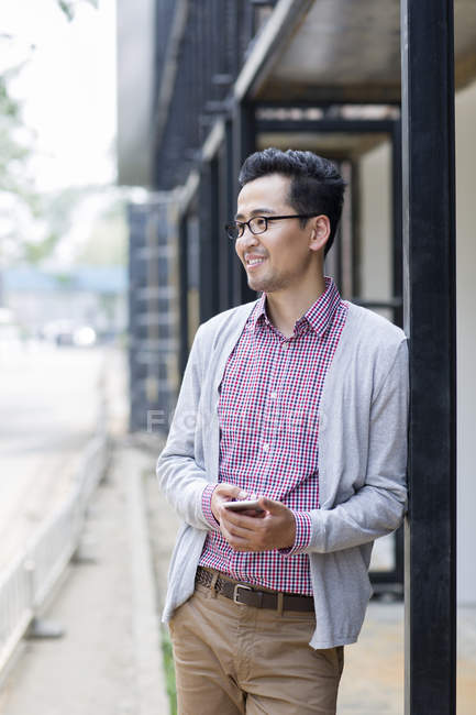 Китайська чоловік стояв на вулиці і проведення смартфон — стокове фото