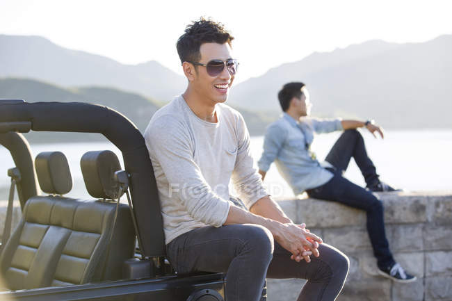 Китайцы сидят на берегу озера и улыбаются. — стоковое фото
