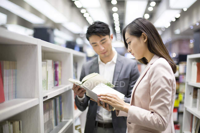 Pareja china eligiendo libros en librería - foto de stock