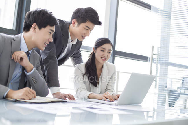 Chinese business people using laptop at meeting — Stock Photo