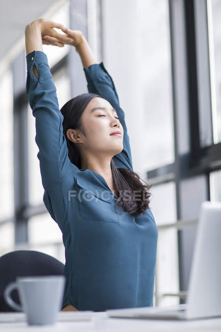 Chinesisch unternehmerin stretching im büro — Stockfoto