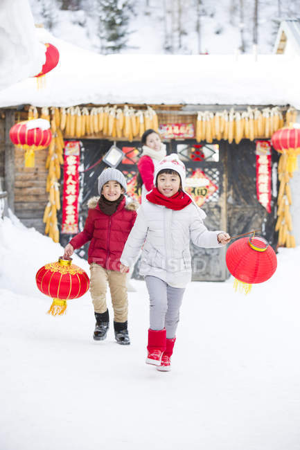 Kinder laufen mit chinesischen Laternen und Mutter im Hintergrund — Stockfoto