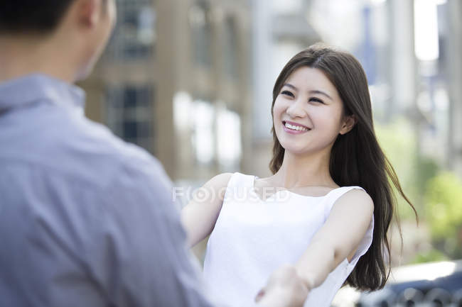Chinesisches Paar hält Händchen und lächelt auf der Straße — Stockfoto