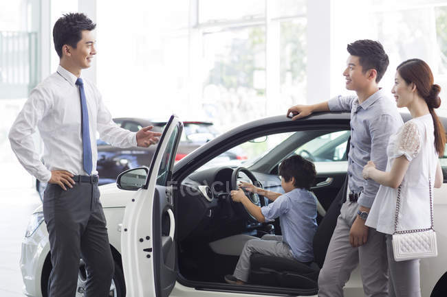 Chinese family choosing car in showroom — Stock Photo
