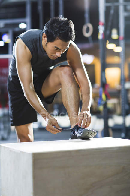 Chinois homme attachant lacets dans la salle de gym — Photo de stock