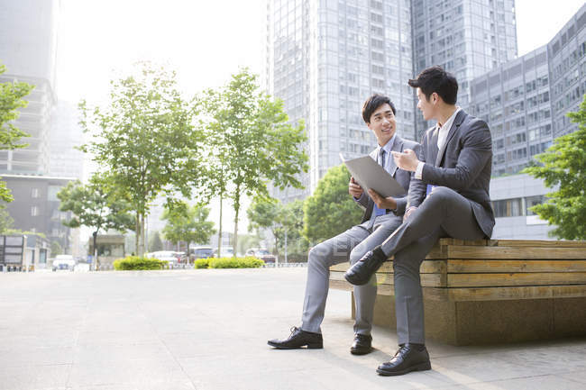 Chinese businessmen discussing work on bench — Stock Photo
