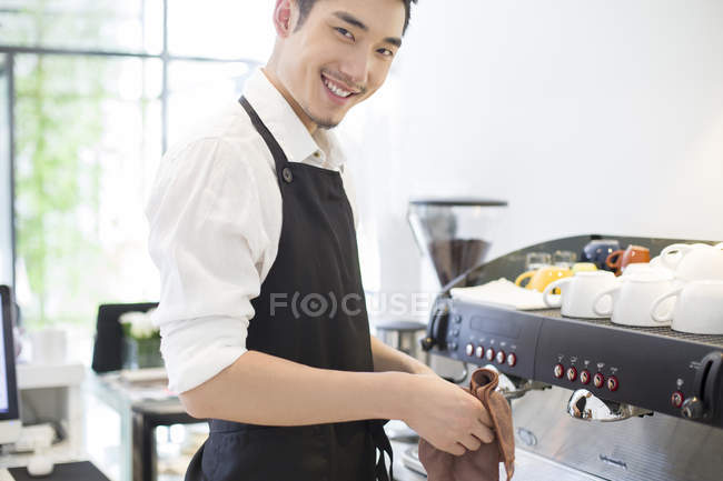 Barista cinese che pulisce l'apparecchio in caffetteria — Foto stock