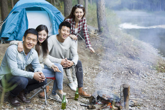 Chinesische Freunde sitzen am Lagerfeuer und bereiten Essen zu — Stockfoto