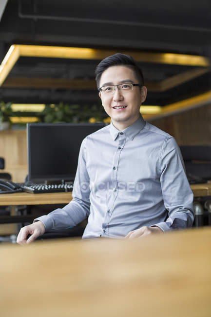 Cinese maschio IT lavoratore seduto sulla sedia sul posto di lavoro — Foto stock