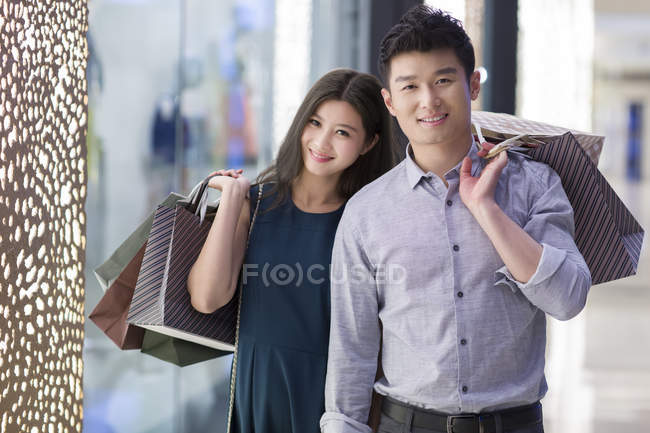 Coppia cinese in piedi con borse della spesa nel centro commerciale — Foto stock