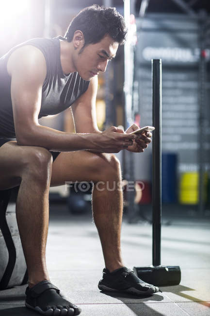 Chinois utilisant smartphone dans la salle de gym — Photo de stock