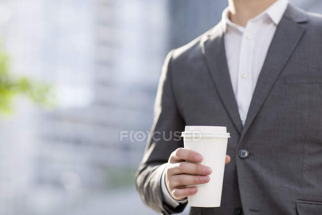 Businessman holding coffee cup on street — Stock Photo