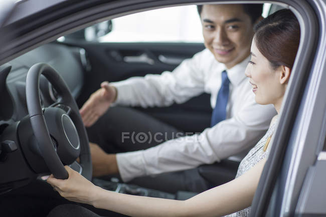 Chinese woman taking test drive with car dealer assistance — Stock Photo