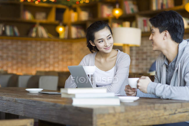 Chinois jeune homme et femme parler avec des tasses de café dans le café — Photo de stock