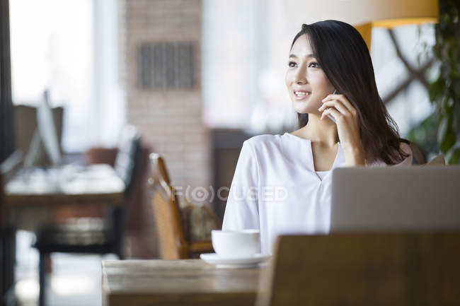Chinese woman talking on phone in cafe — Stock Photo