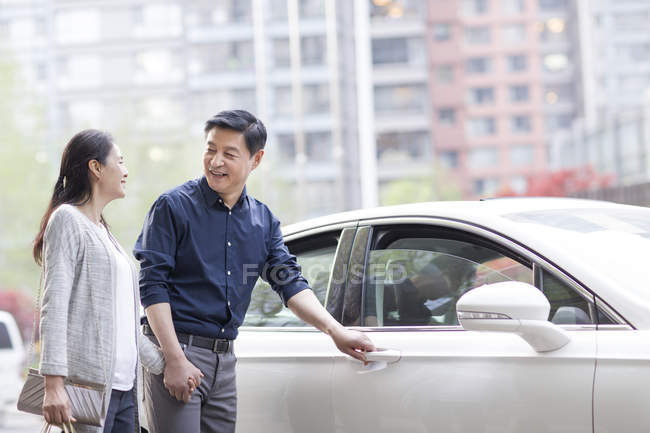 Mature chinese couple getting into car after shopping — Stock Photo