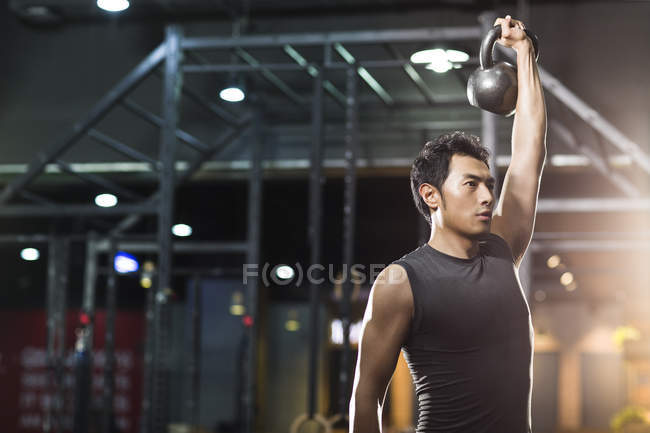 Chinese man training with kettlebell in crossfit gym — Stock Photo