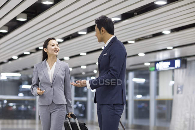 Chinese business people talking in airport with suitcases — Stock Photo