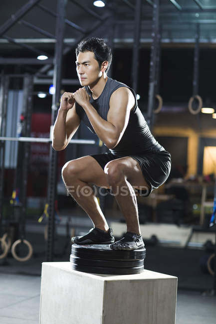 Chinese man doing box jump in crossfit gym — Stock Photo