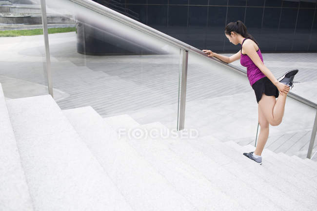 Chinese woman stretching on street stairs — Stock Photo
