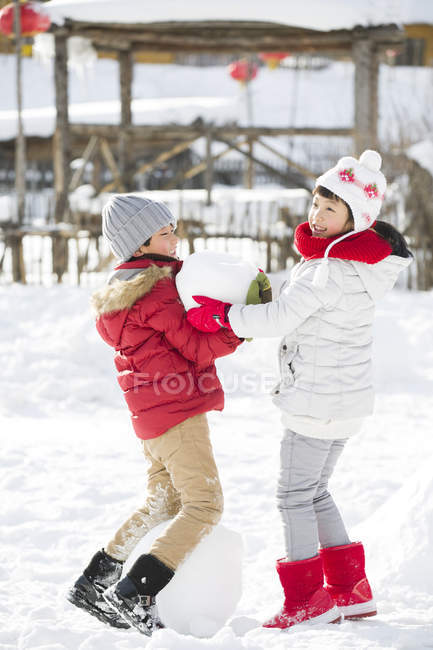 Китайские братья и сестры играют со снежком на открытом воздухе — стоковое фото