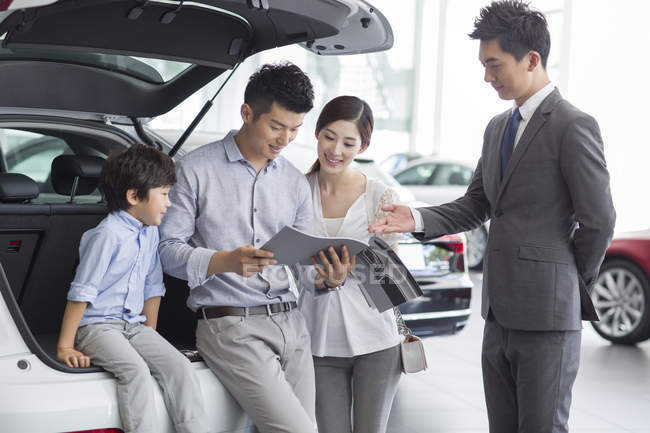 Famiglia cinese con figlio che sceglie auto con rivenditore — Foto stock