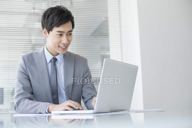 Китайский бизнесмен использует ноутбук в офисе — стоковое фото