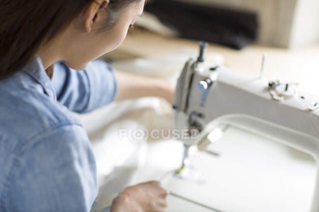 Chinese tailor using sewing machine in atelier — Stock Photo