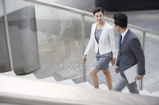 Gente de negocios chinos subiendo escaleras y hablando - foto de stock