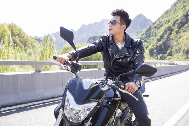 Uomo cinese seduto sulla moto in autostrada — Foto stock
