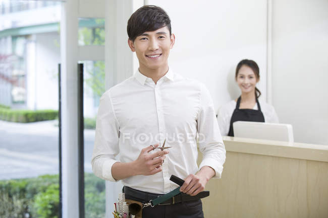 Chinese hairdressers standing in shop with pair of scissors — Stock Photo