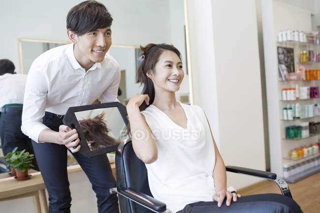 Chinese woman looking in mirror at hair in salon — Stock Photo