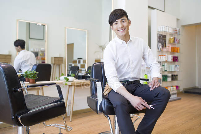 Chinese hairdresser sitting in chair in barber shop — Stock Photo