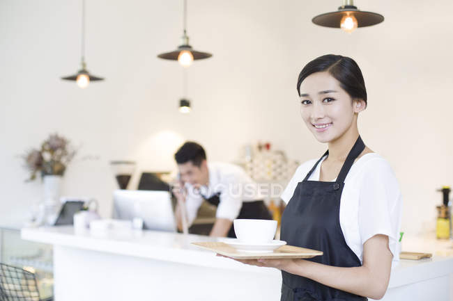 Chinese coffee shop waitress standing with cup of coffee — Stock Photo