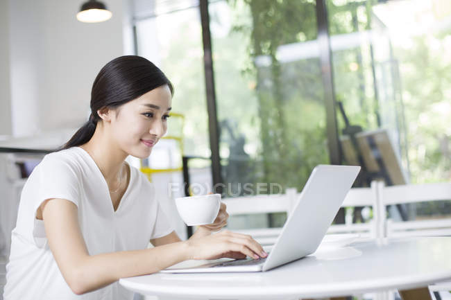 Chinese woman using laptop in coffee shop — Stock Photo