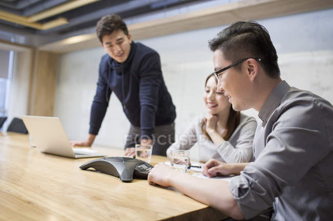 Compañeros chinos que tienen teleconferencia en la sala de reuniones - foto de stock