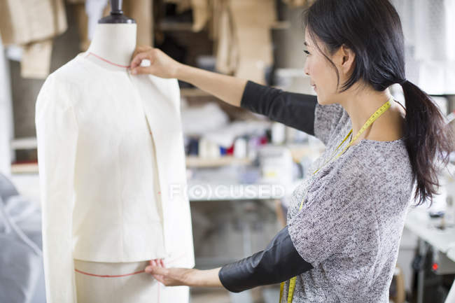 Diseñador de moda chino trabajando con maniquí en estudio - foto de stock