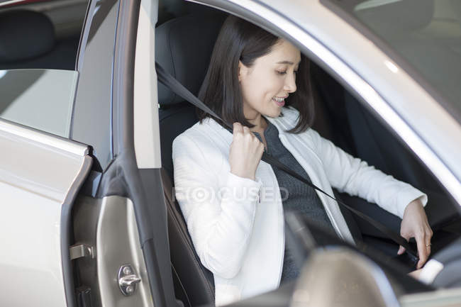 Молодая китаянка пристегивает ремни в машине — стоковое фото