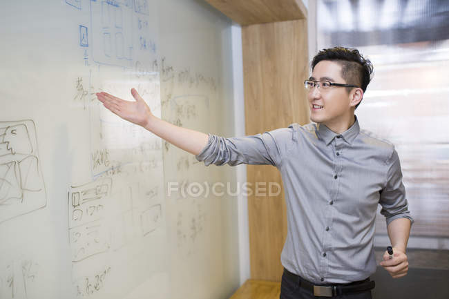 Chinesischer Geschäftsmann zeigt Plan auf Whiteboard — Stockfoto