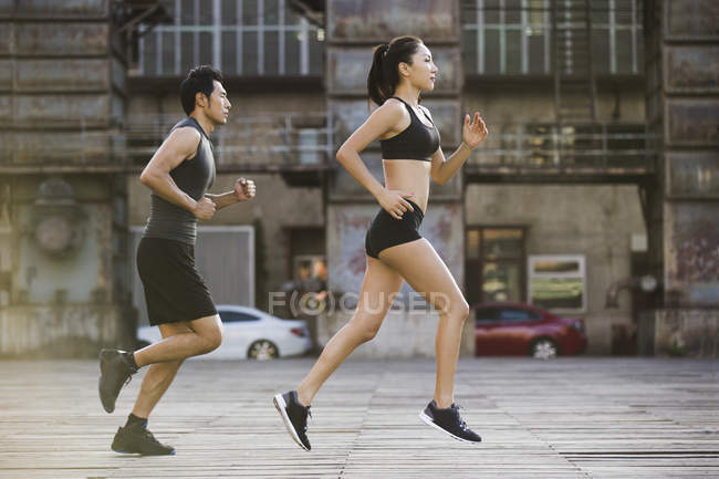 Couple of chinese joggers running at street — Stock Photo