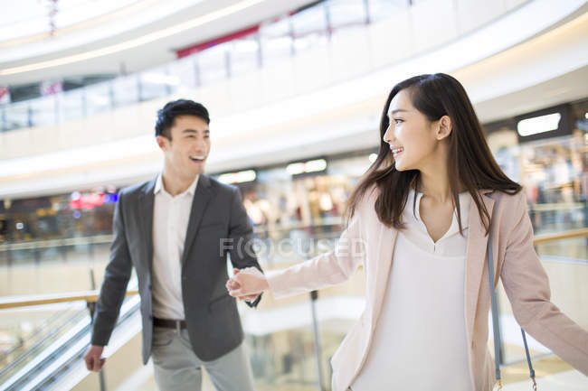 Chinese couple holding hands in shopping mall — Stock Photo