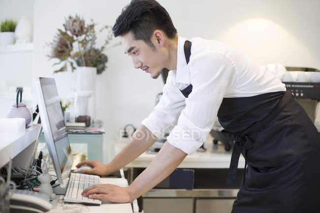 Chinese coffee shop owner using computer — Stock Photo