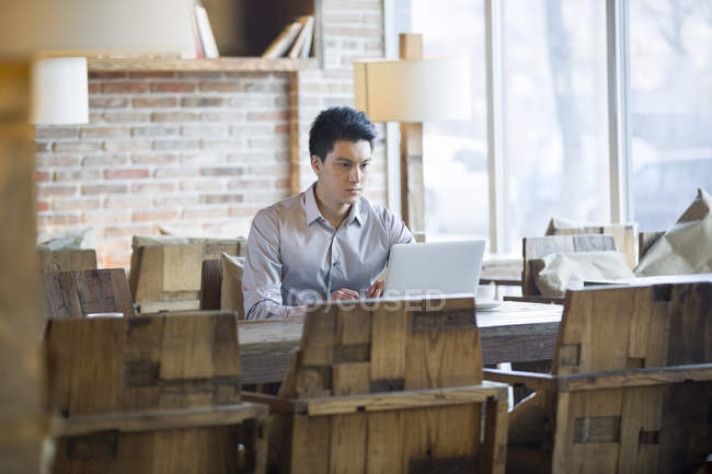 Homem chinês trabalhando com laptop no café — Fotografia de Stock